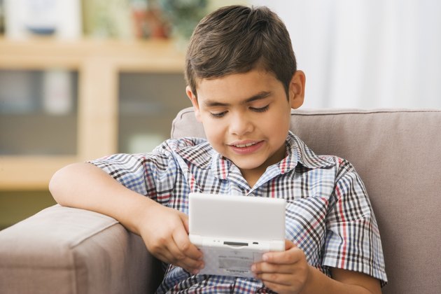 Hispanic boy playing handheld video game on sofa