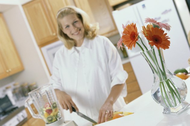 Portrait of a young pregnant woman cutting fruit