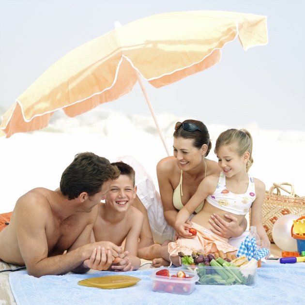 Parents with daughter (8-9 years) and son (12-13 years) eating snacks on beach