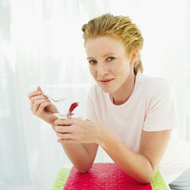 Young woman holding a strawberry yoghurt and a spoon