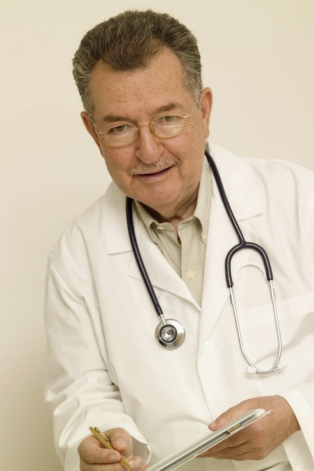 Senior doctor writing on patient's chart