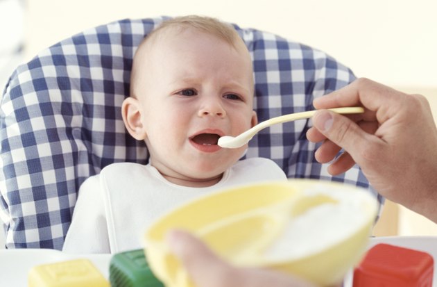 Father feeding baby (6-12 months), indoors