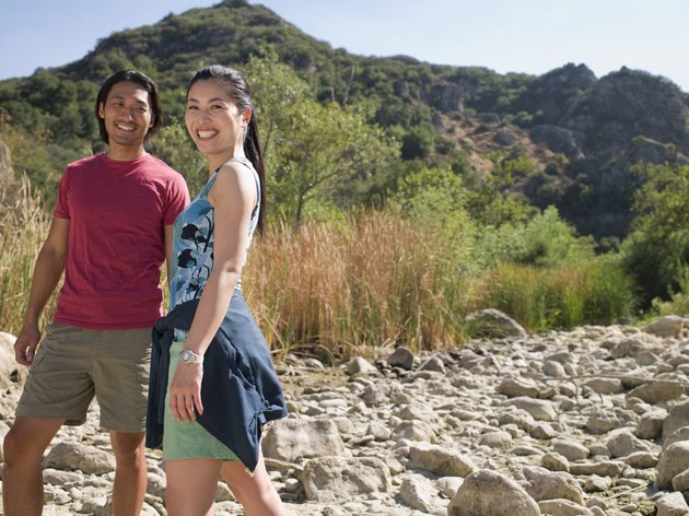 Smiling young couple walking in dry riverbed