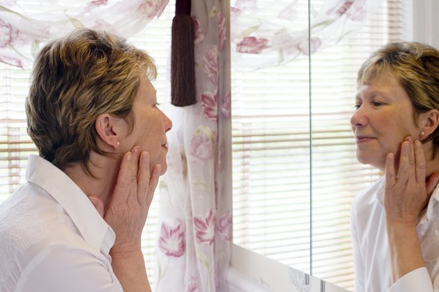 Mature woman looking at face in mirror