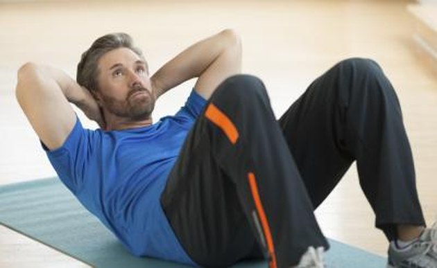Mature man doing sit-ups on exercise mat at home