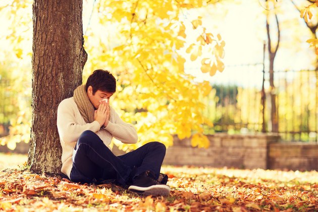 ill man with paper tissue in autumn park