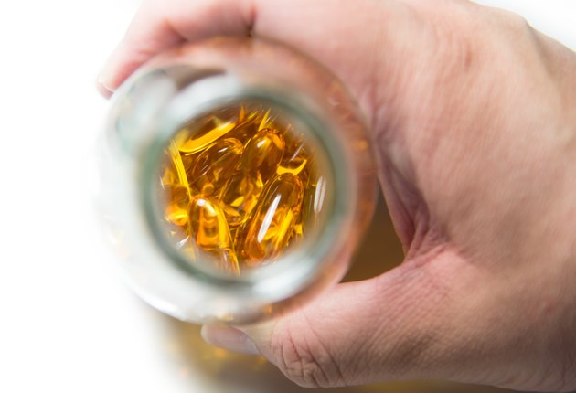 Male hand hold bottle of fish oil over white