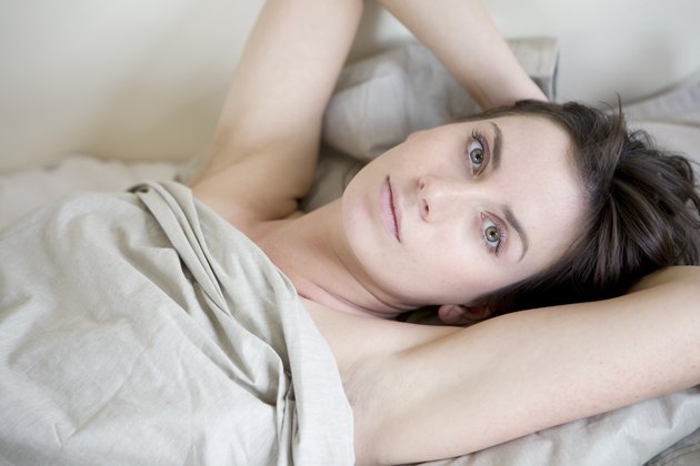 pensive brunette woman lying on bed