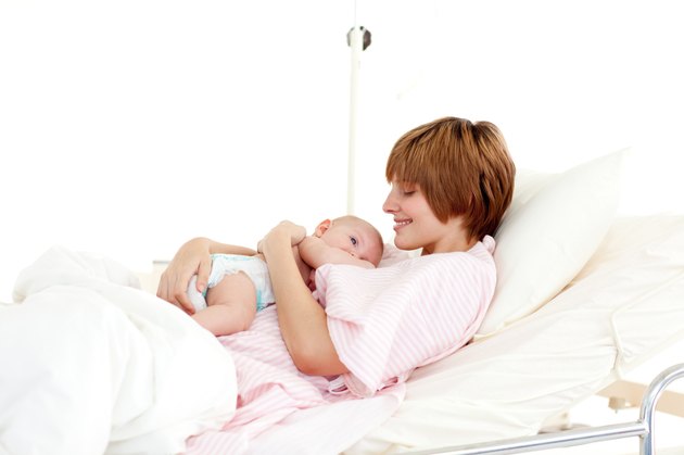 Smiling patient with newborn baby in bed