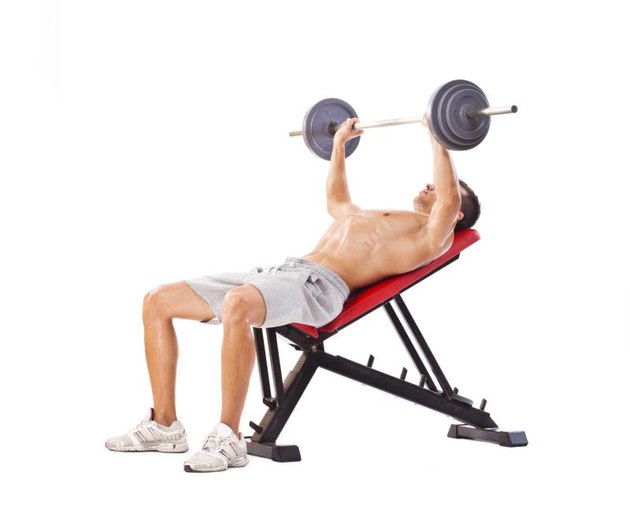 Handsome man doing incline bench press. Studio shot, isolated on white.