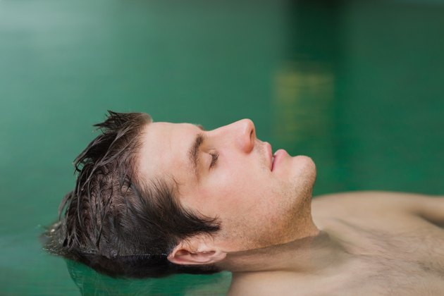 Handsome man floating in the pool