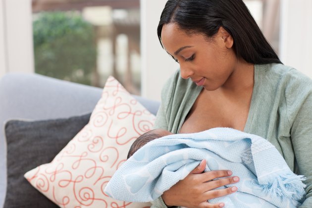 Young woman holding baby son in blanket