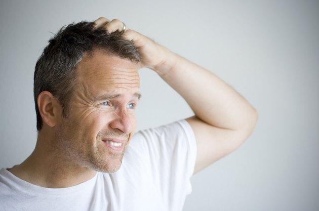 Man with bedhead trying to cover his hair with hand