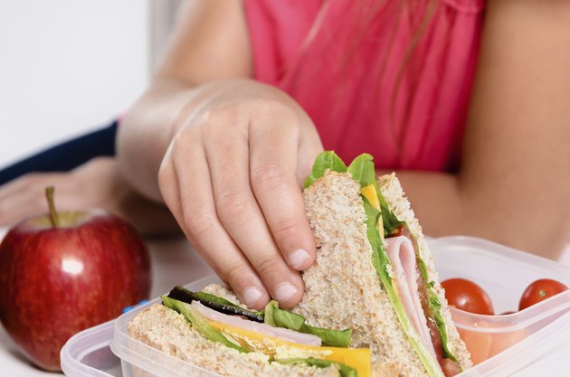 Child removing wholemeal sandwich out of lunchbox