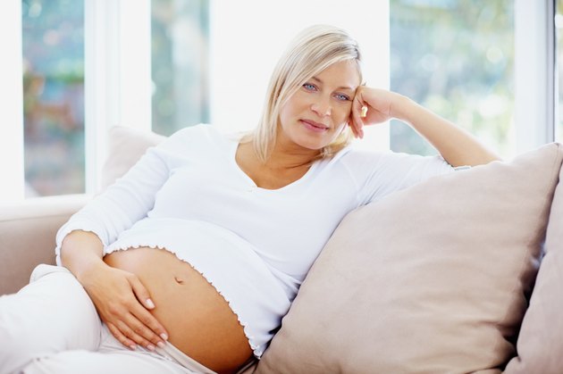 Thoughtful mature pregnant woman relaxing on couch