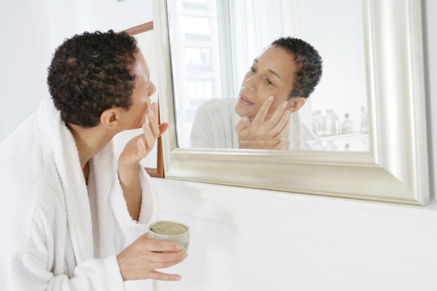 African American woman applying face mask.