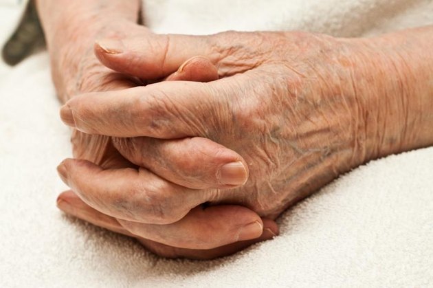 old hands clasped on knees