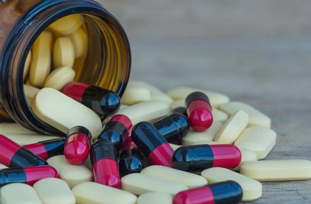 Many Pills and vitamin in Medicine bottles on wood background
