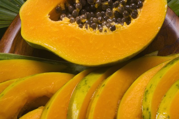 Studio shot of papaya, halved and cut into slices.