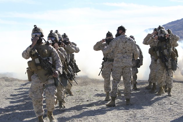 Marines and sailors participate in an outdoor gas exercise in full protective gear.