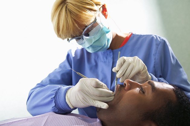 A dental hygienist works on a patient's mouth during a dental exam