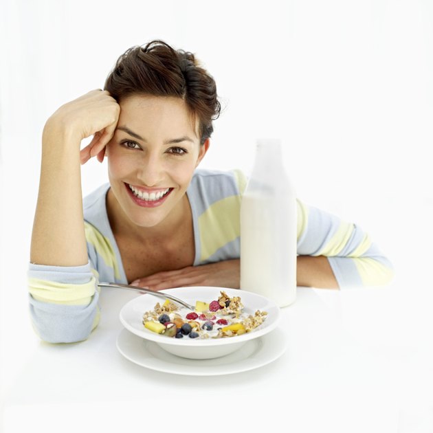 portrait of a young woman sitting with a bowl of breakfast cereal and milk