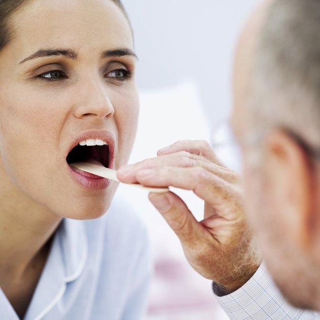 doctor examining with a woman with a tongue depressor