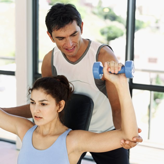 close-up of an instructor training a woman with dumbbells