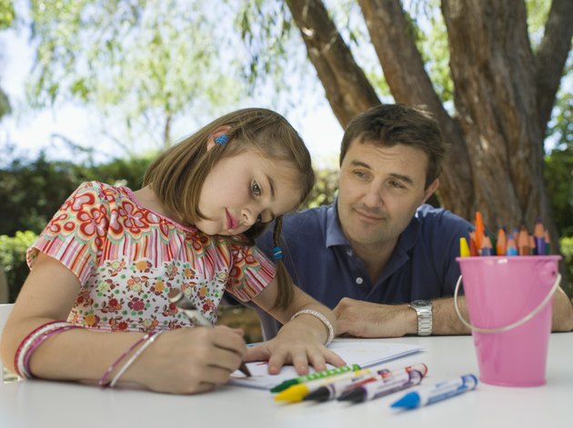 Girl drawing as father watches
