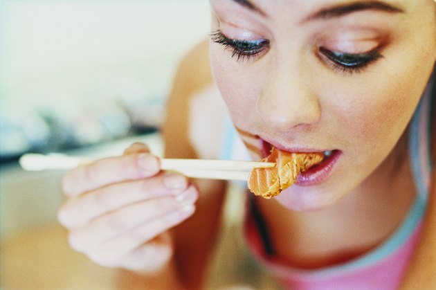 Close up of Young Woman Eating a Piece of Sushi With Chopsticks