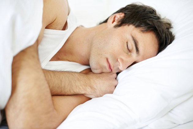 Handsome young guy sleeping in bed