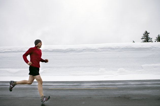 一名男子在大雪中沿着道路慢跑。