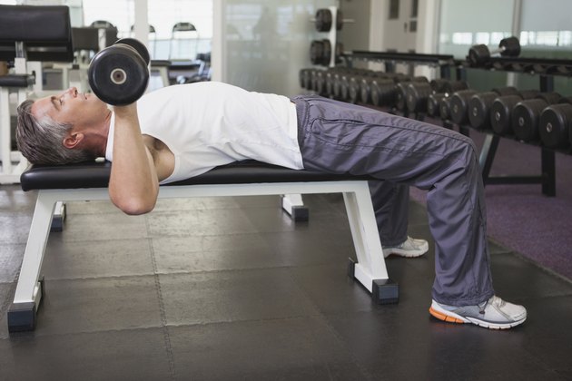 Fit man lifting dumbbells lying on the bench