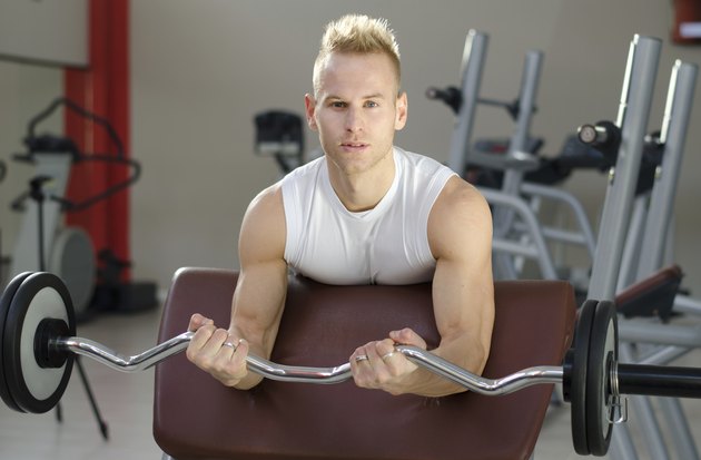 Handsome young man training biceps in gym