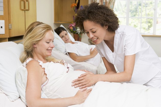 Nurse checking pregnant womans belly and smiling