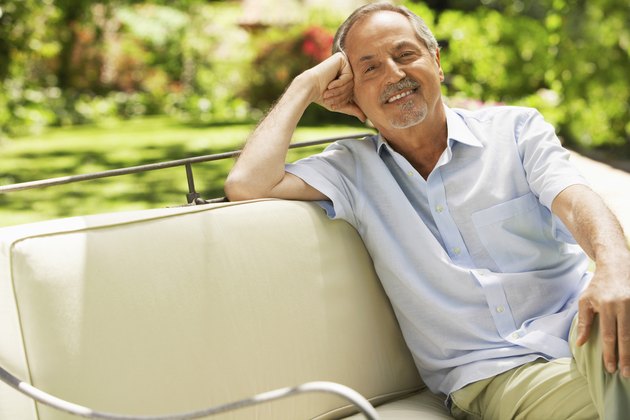 Senior Man Sitting On Sofa In Backyard
