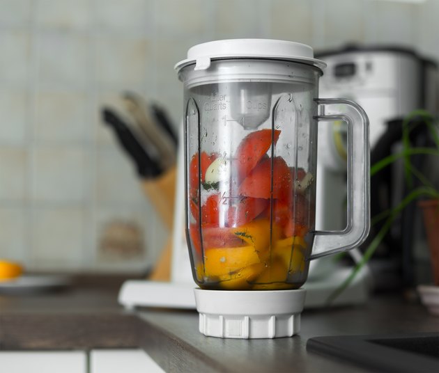 Blender with fresh vegetables on kitchen table