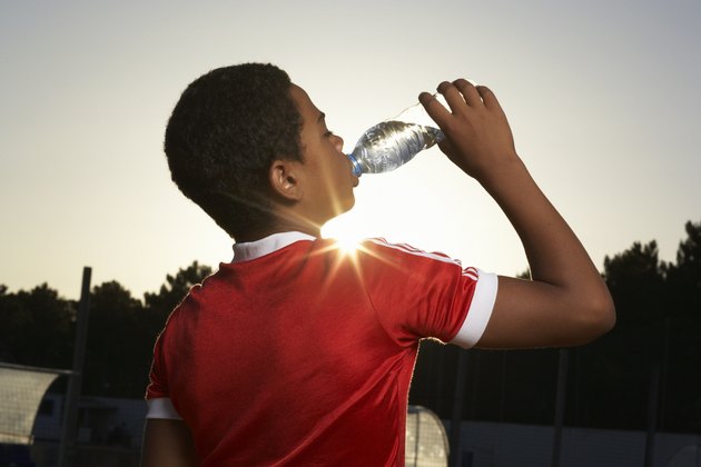 Boy (12-13) drinking water, rear view