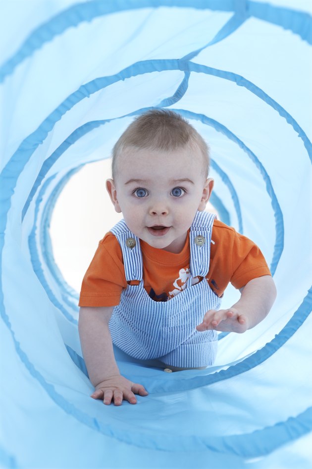Baby boy (11-13 months) crawling through play tunnel