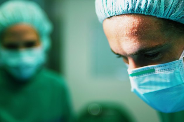 "Operating theatre team at work, surgeons with sweaty brow, close-up"