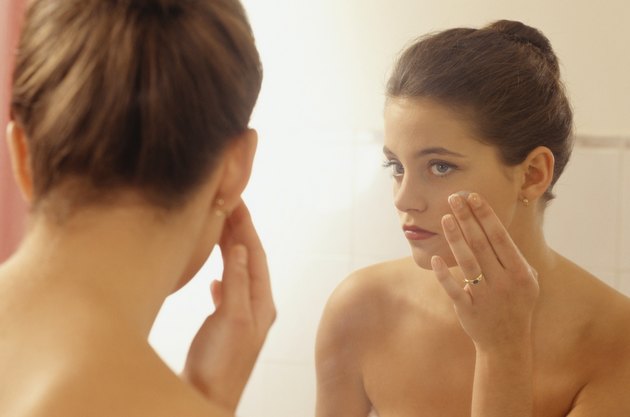 Young woman in bathroom, doing make up in front of mirror, close-up
