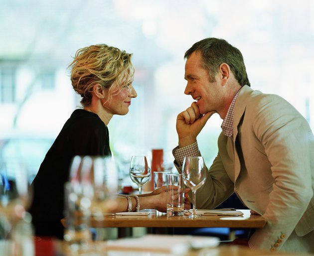 Couple sitting face-to-face at restaurant table, smiling