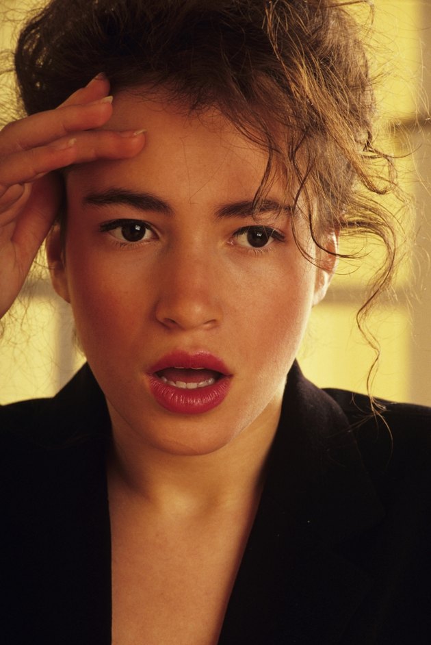 Young woman touching forehead with hand
