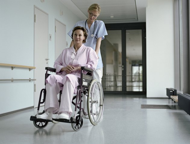 Young female doctor pushing female patient in wheelchair