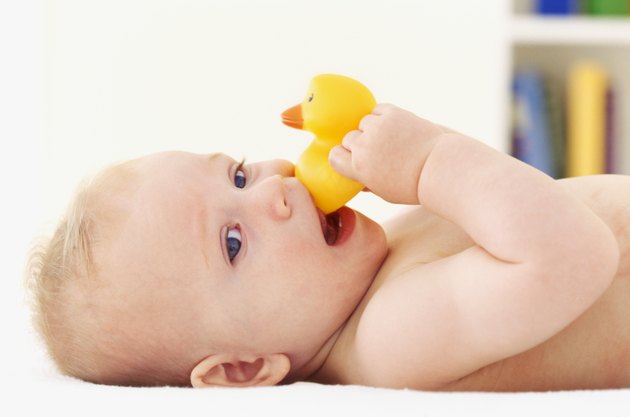 Close-up of baby girl lying down holding rubber duck
