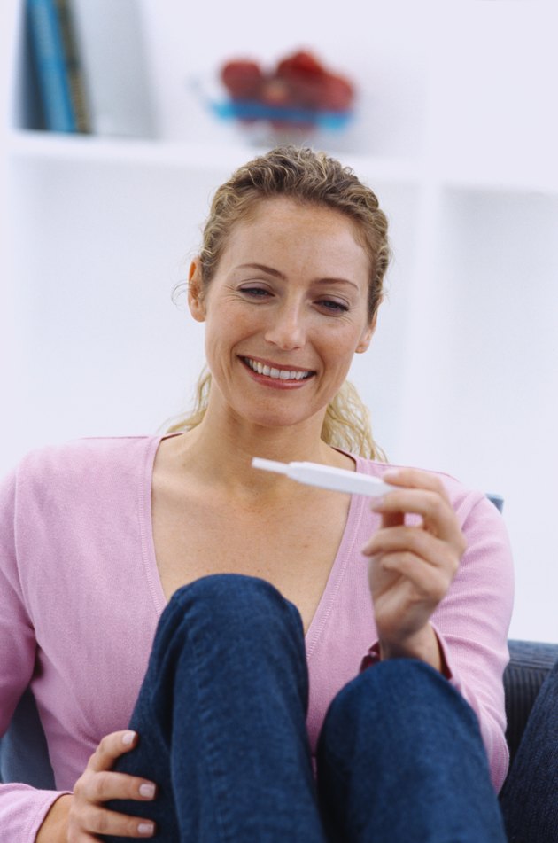 Woman looking at a pregnancy test in her hand and smiling