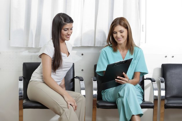 Dentist And Patient Looking At Clipboard