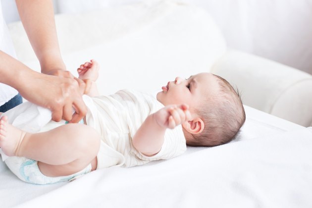 Close-up of a young mother changing the nappy of her baby lying on a couch