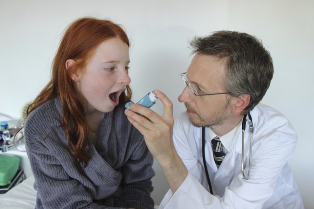 Hospital doctor showing young girl how to use salbutamol inhaler