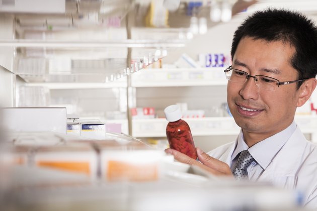 Pharmacist taking down and examining prescription medication in a pharmacy